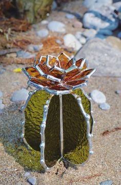 a glass flower sitting on top of a sandy beach