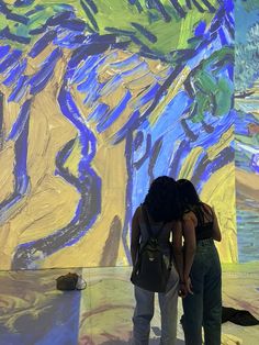 two people standing in front of a painting on the wall with their backs to each other