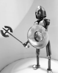 a metal figurine is holding a wrench