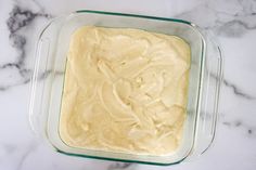 a glass casserole dish filled with batter on top of a marble countertop