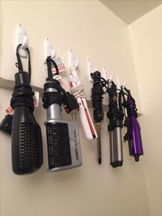 several different types of hair dryers hanging on a wall