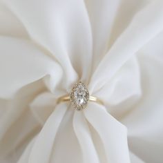 a diamond ring sitting on top of a white satin material with a knot in the middle