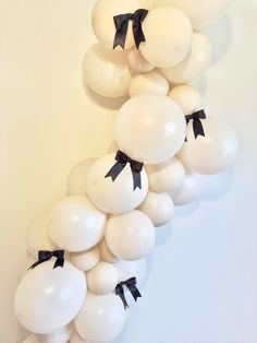 white balloons with black bows on them are arranged in the shape of a spiral staircase