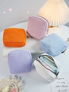 four different colored purses sitting on top of a white table next to a lamp