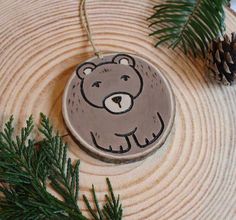 a brown bear ornament sitting on top of a wooden tree stump next to pine cones