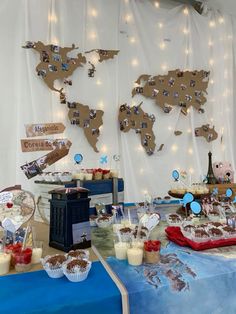 a table topped with cakes and cupcakes next to a map of the world