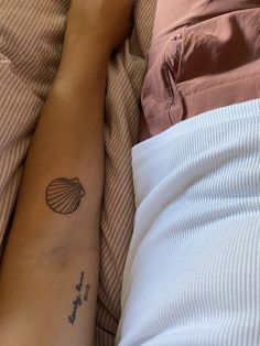 a person with a small tattoo on their arm laying in bed next to a pillow