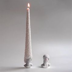 a white candle with a human head next to it