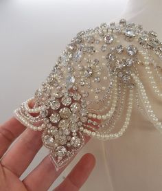 a hand is holding a bridal garter with pearls and crystals on the side