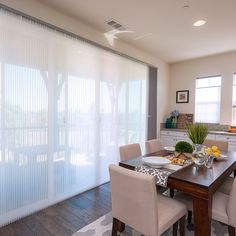 the dining room table is set with place settings for four people and has white curtains