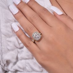 a woman's hand with a diamond ring on top of her finger and white nails