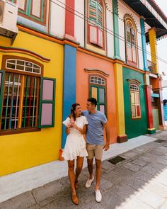 a man and woman standing in front of colorful buildings