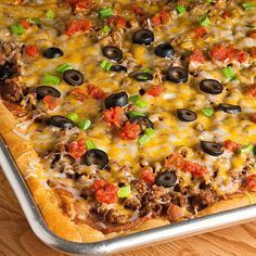 a square pizza with cheese, olives and ground beef on a wooden table top