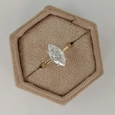 an engagement ring with a pear shaped diamond on it in a hexagonal box