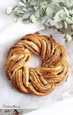 a pastry is sitting on a piece of parchment paper next to some flowers and leaves