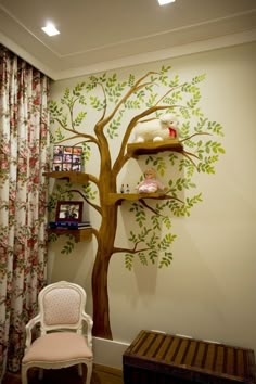 a room with a tree painted on the wall next to a chair and table in front of it