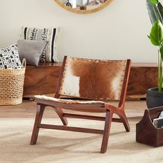 a wooden chair sitting on top of a rug next to a potted plant and mirror