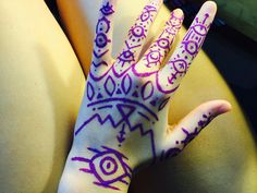 a person's hand painted with purple and white designs on it, sitting in front of a laptop