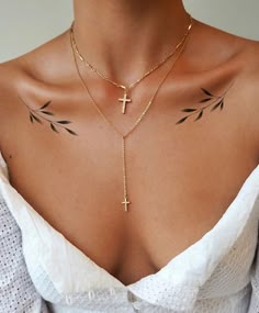 a woman with tattoos on her chest wearing a white top and gold chain choker