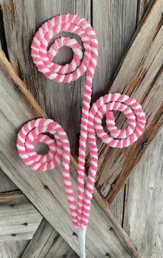 pink and white striped lollipops sitting on top of a wooden table