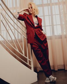 a woman in a red suit leaning against a railing