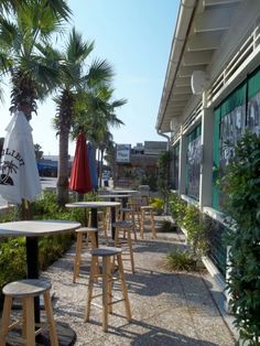 tables and stools outside an outdoor cafe with palm trees