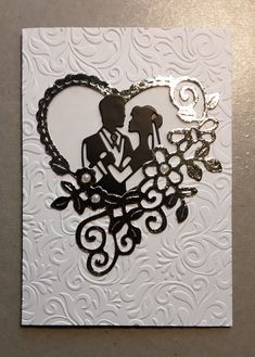 a wedding card with a silhouette of a bride and groom in a heart - shaped frame