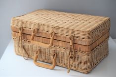 two wicker baskets stacked on top of each other with straps around the handles and sides