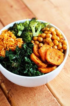 a white bowl filled with broccoli, chickpeas and sweet potato wedges