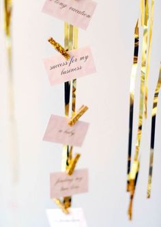 some gold colored items hanging from strings with name tags attached to the ends and on them