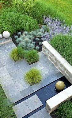 an outdoor garden with water and plants in the center, surrounded by stone blocks and grass