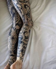 a person laying in bed with tattoos on their arms and legs, both covered by white sheets