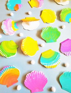 many different colored seashells on a gray surface with white balls in the background