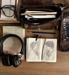 an assortment of books, headphones and notebooks on a wooden table next to a bag