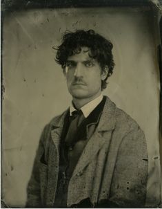 an old black and white photo of a man with curly hair wearing a suit jacket