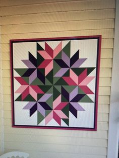 a quilt hanging on the side of a house