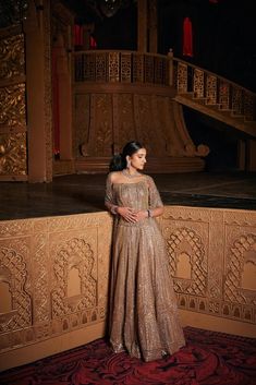 a woman in a gold gown standing on a red carpet next to a stair case