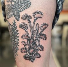 a close up of a person's legs with tattoos on them and flowers in the background