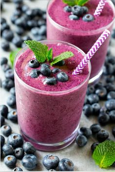 two glasses filled with blueberry smoothie on top of a table