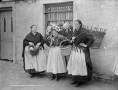 three women standing next to each other in front of a building with baskets on their heads