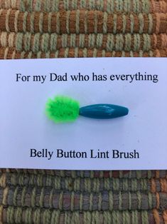 a green toothbrush sitting on top of a white sign that says, for my dad who has everything belly button lint brush