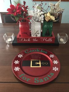 a red plate sitting on top of a wooden table next to vases filled with flowers