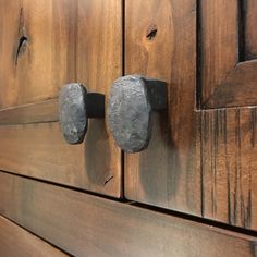 two metal knobs on the side of a wooden cabinet door with wood grained doors