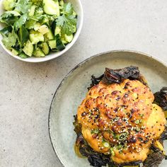 a plate with some food on it next to a bowl of salad