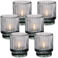 four clear glass votive candles are set on a white background