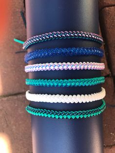 several different colored bracelets sitting on top of a black pole next to a brick wall