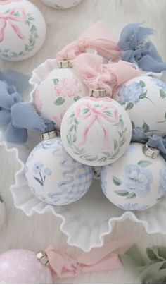 an arrangement of decorated christmas balls on a table with ribbons and bows around the ornaments