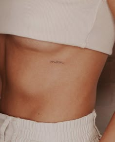 a woman's stomach with the word mom tattooed on her left side ribcage