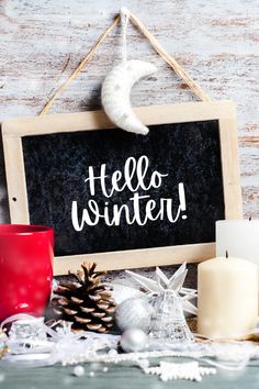 a chalkboard with the words hello winter written on it next to christmas decorations and candles