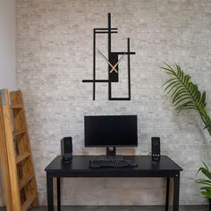 a desk with a computer on it in front of a brick wall and a plant